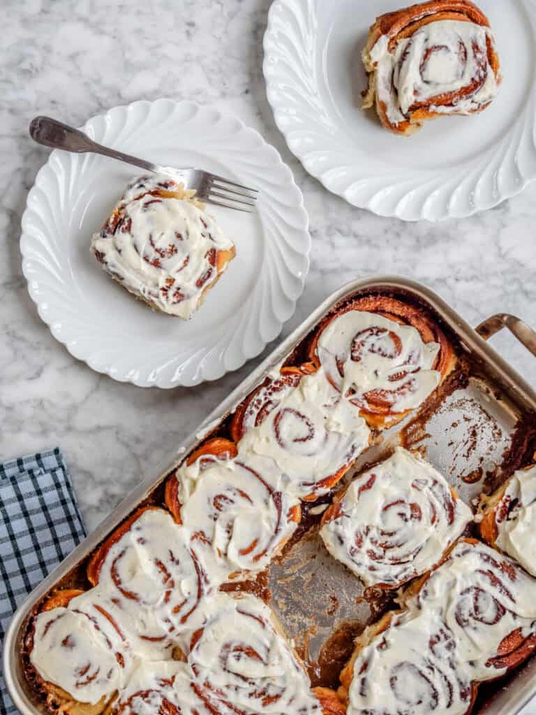 Kanelsnegle i fad med kanelremonce, fløde og cream cheese frosting, bagt gyldne og samlet tæt i et fad.